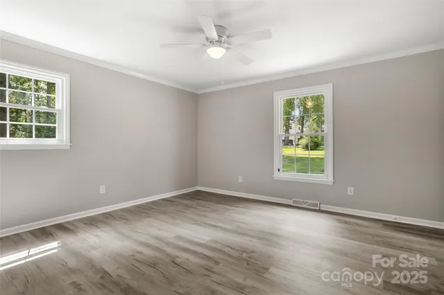 an empty room with windows and ceiling fan
