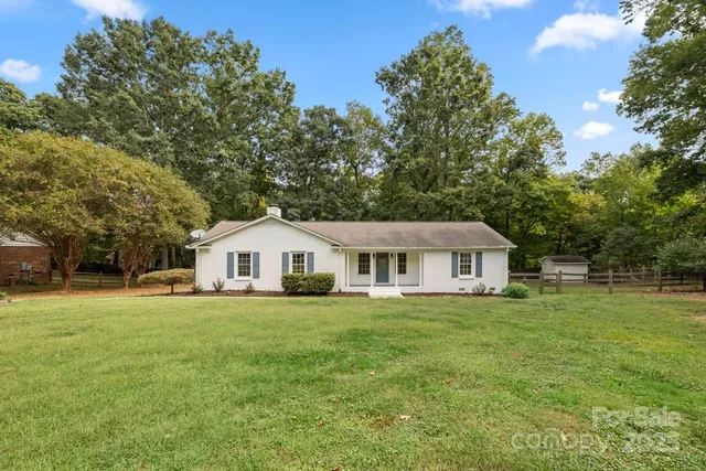 a white house with a big yard and large trees