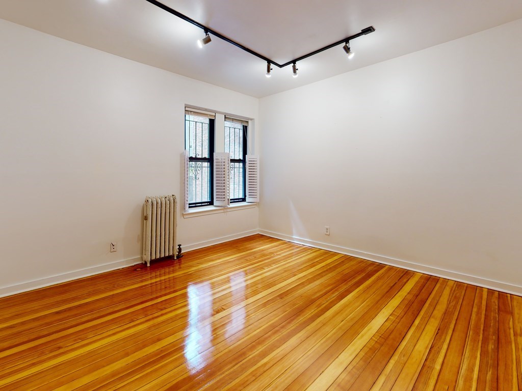 1404 Commonwealth Avenue, Unit 7 Boston, MA 02135 - Photo 13 of 19 a view of an empty room with a window and wooden floor