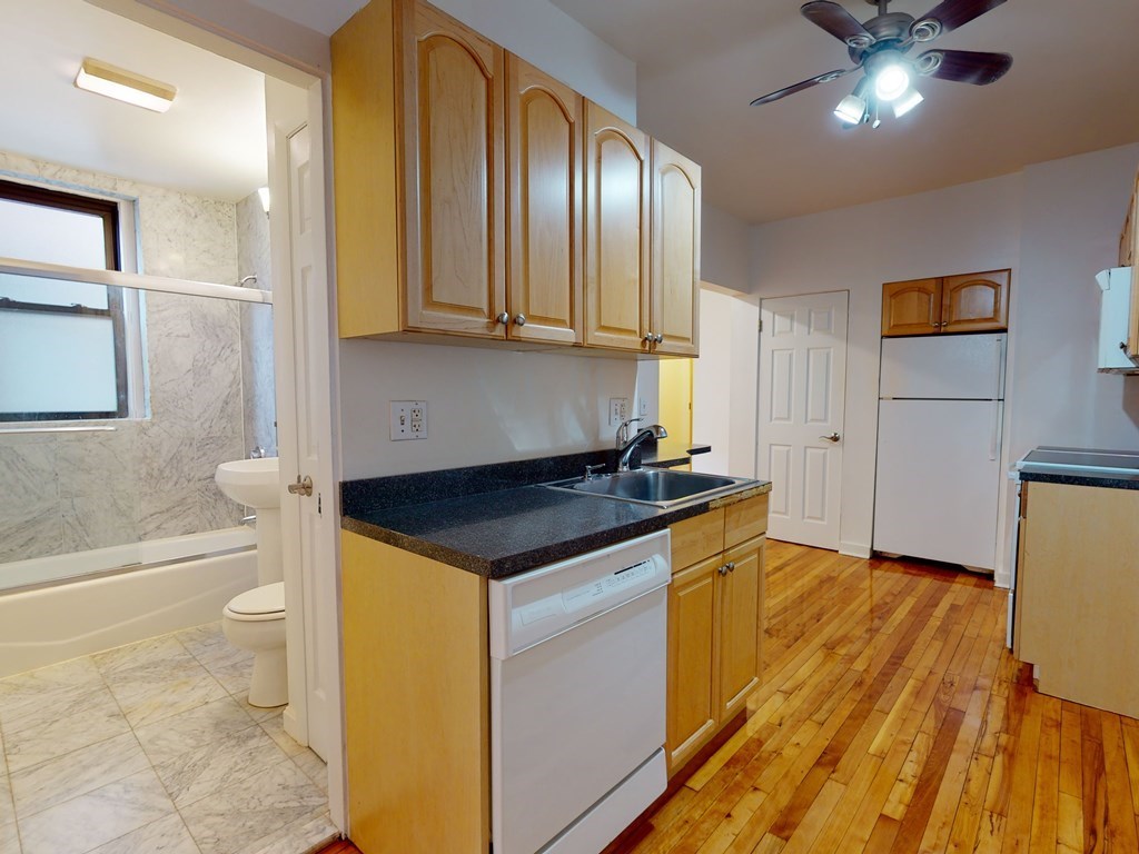 1404 Commonwealth Avenue, Unit 7 Boston, MA 02135 - Photo 7 of 19 a kitchen with a sink and wooden cabinets