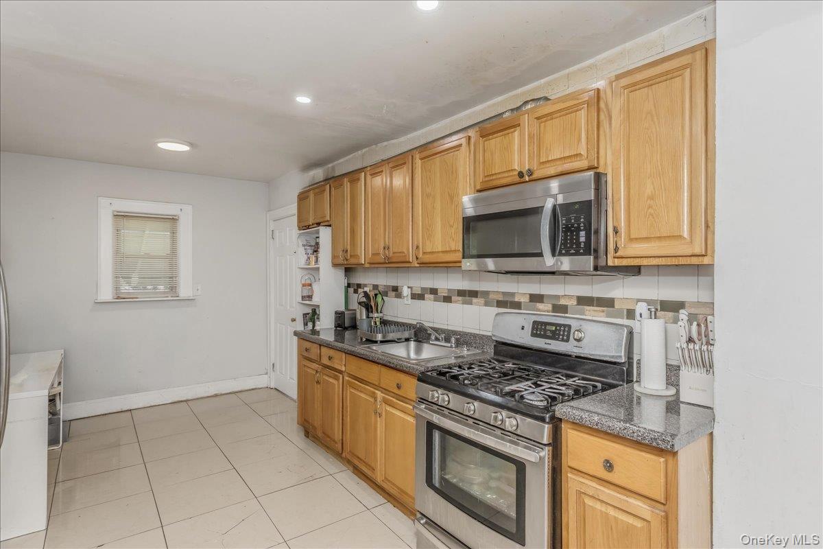 237 Rhodes Avenue Hempstead, NY 11550 - Photo 10 of 24 a kitchen with granite countertop a stove top oven microwave and cabinets