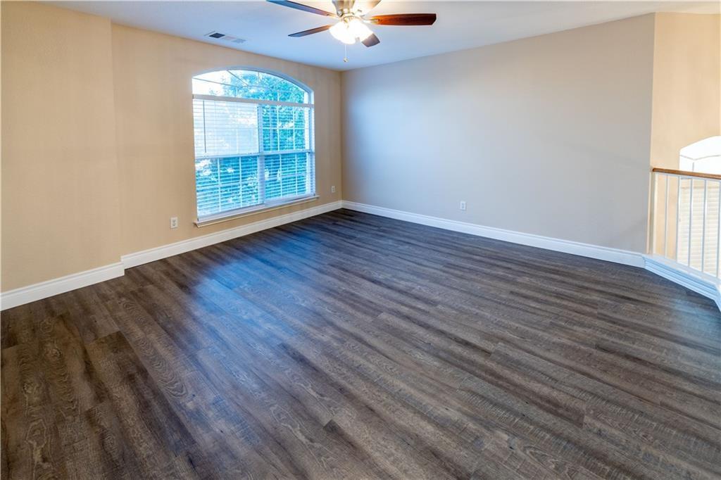 12017 Springs Head Loop Austin, TX 78717 - Photo 12 of 25 A spacious room offers rich wood flooring and abundant natural light from a large arched window.