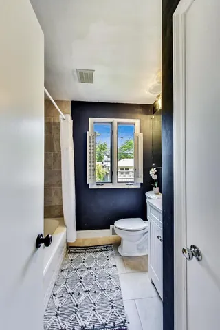 a bathroom with a toilet a window and tub