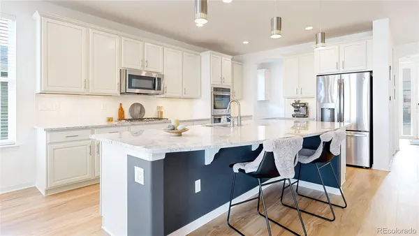 a kitchen with stainless steel appliances kitchen island granite countertop a sink a stove a refrigerator and cabinets