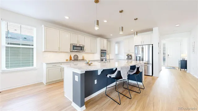 a kitchen with stainless steel appliances granite countertop a refrigerator a sink dishwasher a stove and white countertops with wooden floor