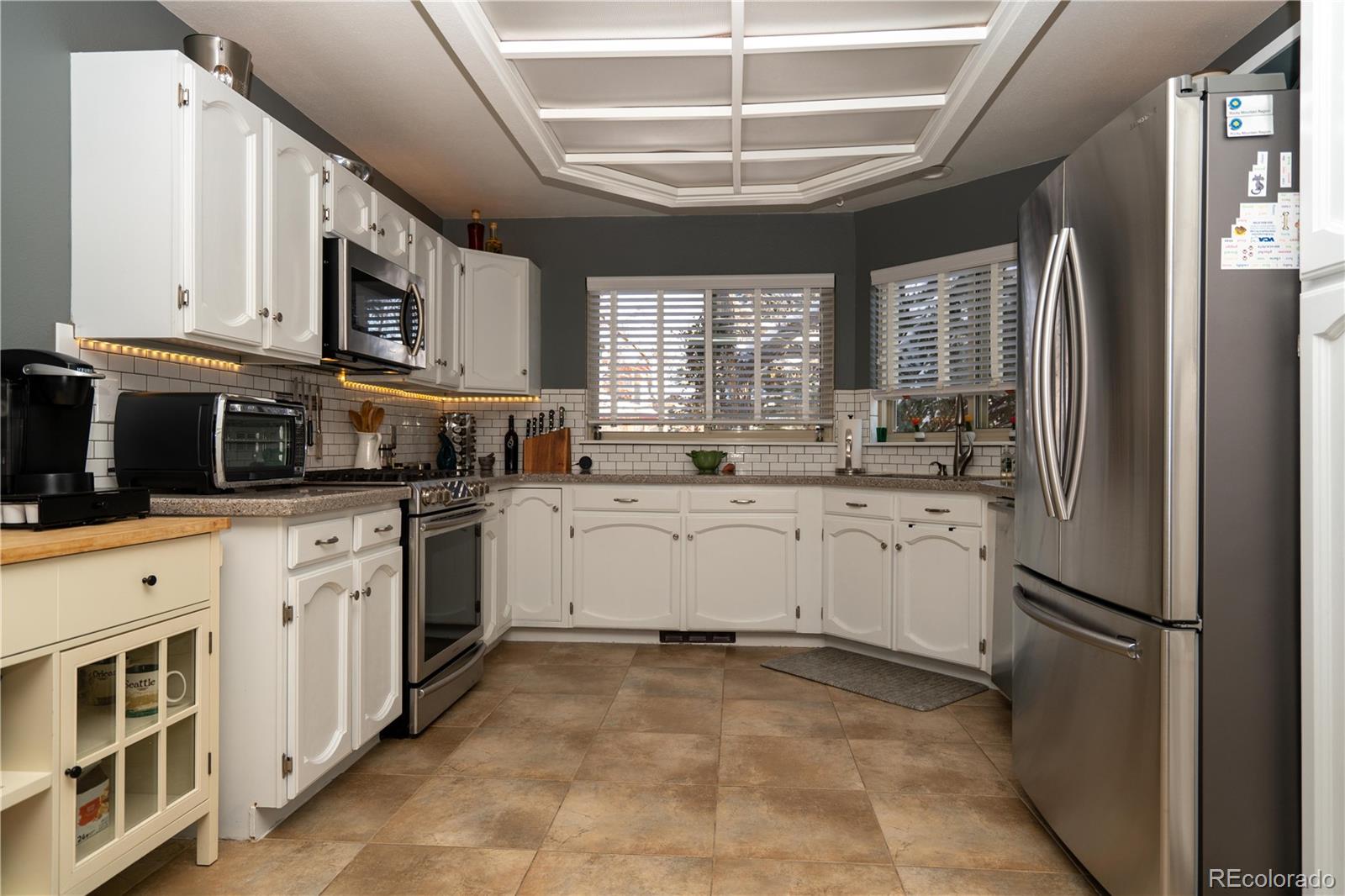 8583 Redstone Street Highlands Ranch, CO 80126 - Photo 11 of 17 a kitchen that has a lot of white cabinets and stainless steel appliances