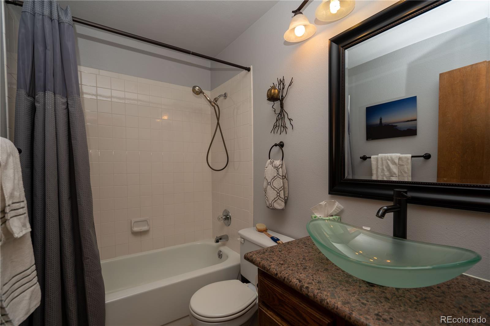 8583 Redstone Street Highlands Ranch, CO 80126 - Photo 9 of 17 a bathroom with a granite countertop sink toilet and shower
