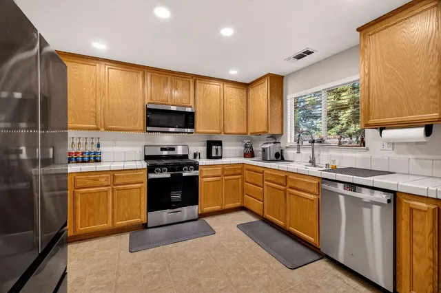 a kitchen with stainless steel appliances granite countertop a stove a sink and a microwave