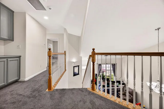 a view of a hallway with white cabinets and refrigerator