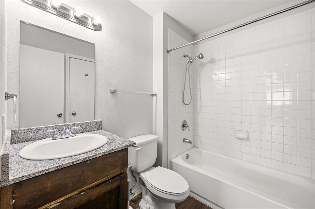 9837 Walnut Street, Unit S203 Dallas, TX 75243 - Photo 12 of 26 Bathroom with a vanity featuring a granite countertop and a white oval sink, a toilet, and a bathtub with white tile surround