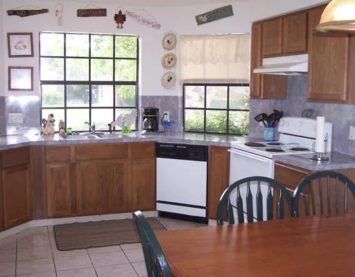 a kitchen with stainless steel appliances granite countertop a stove top oven a sink a dining table and chairs