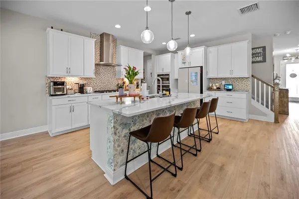a kitchen with stainless steel appliances kitchen island granite countertop a table chairs refrigerator and microwave