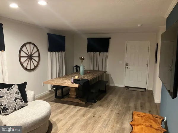 a living room with couches a flat screen tv and a large window with wooden floor