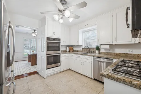 a kitchen with stainless steel appliances white cabinets and stove top oven