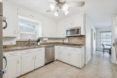 a kitchen with granite countertop white cabinets white stainless steel appliances with a sink and dishwasher