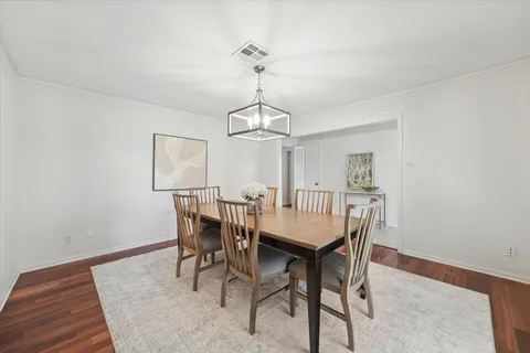 a dining room with furniture a chandelier and wooden floor