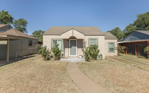 a front view of a house with a yard and potted plants