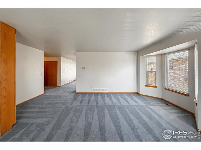 a view of an empty room with wooden floor and window