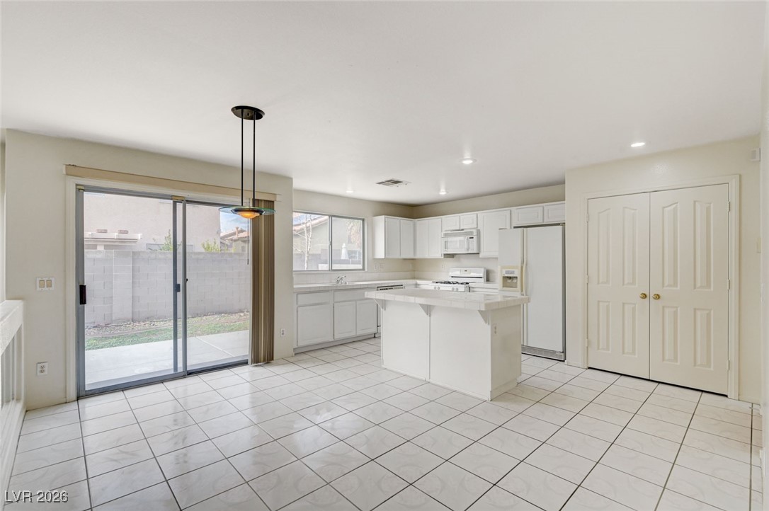 3901 Triora Street Las Vegas, NV 89129 - Photo 13 of 42 Kitchen featuring white cabinets, light countertops, white appliances, decorative light fixtures, and a kitchen island