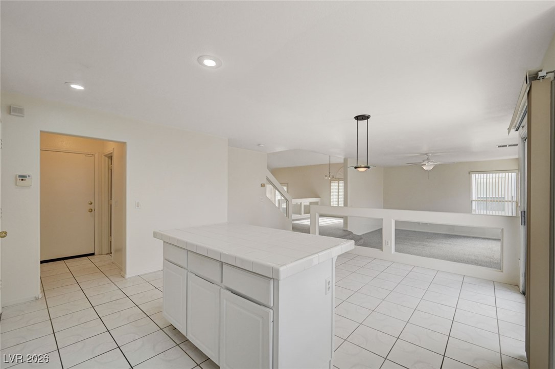 3901 Triora Street Las Vegas, NV 89129 - Photo 16 of 42 Kitchen with tile countertops, white cabinetry, plenty of natural light, and hanging light fixtures