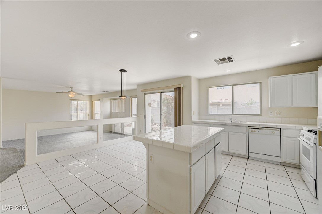 3901 Triora Street Las Vegas, NV 89129 - Photo 42 of 42 Kitchen featuring tile countertops, open floor plan, white cabinets, decorative light fixtures, and white appliances