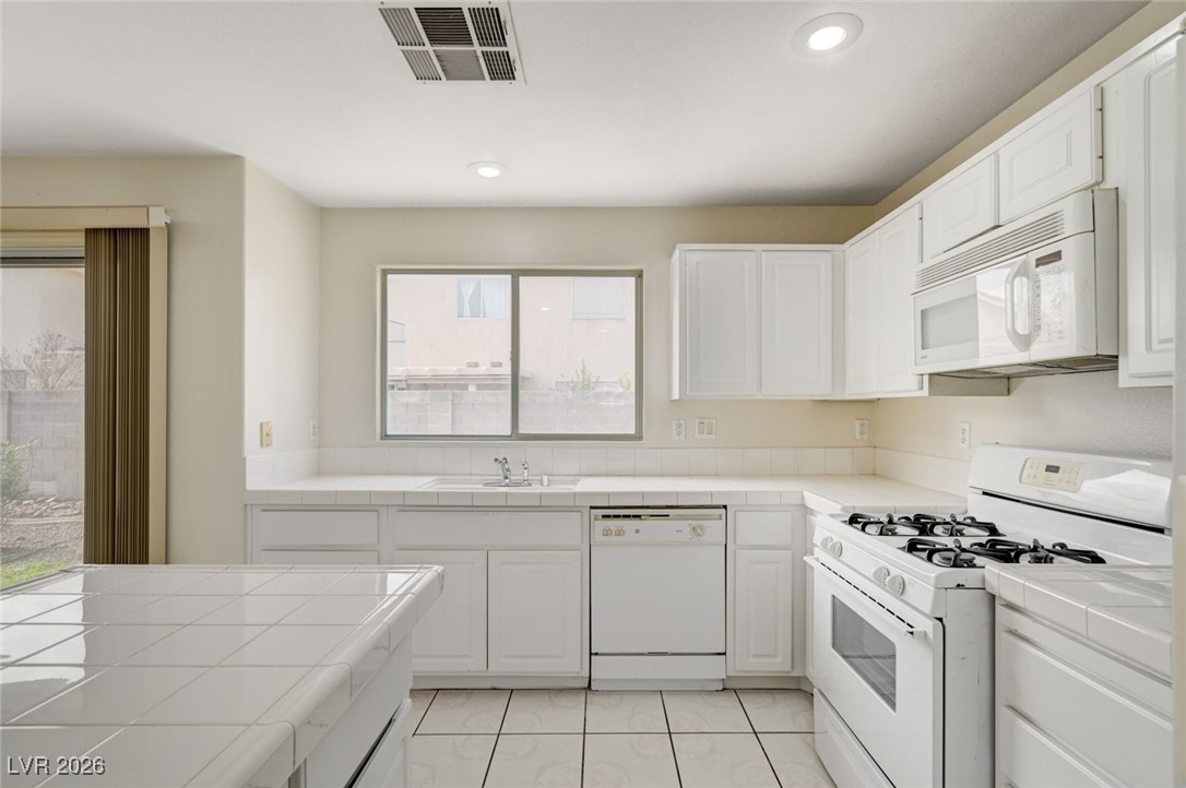 3901 Triora Street Las Vegas, NV 89129 - Photo 17 of 42 Kitchen featuring tile countertops, white appliances, white cabinetry, and recessed lighting