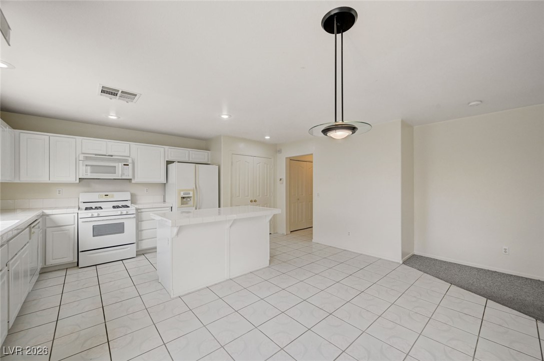 3901 Triora Street Las Vegas, NV 89129 - Photo 18 of 42 Kitchen featuring white appliances, white cabinetry, a center island, pendant lighting, and recessed lighting
