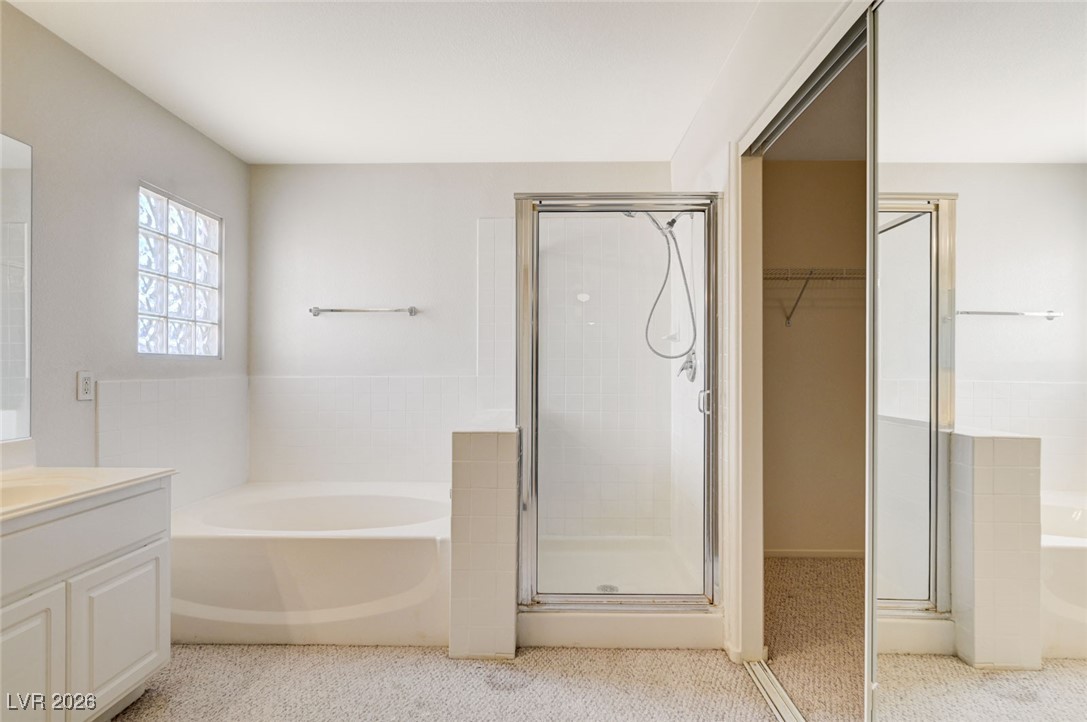 3901 Triora Street Las Vegas, NV 89129 - Photo 22 of 42 Full bath with a garden tub, vanity, a shower stall, a walk in closet, and light colored carpet