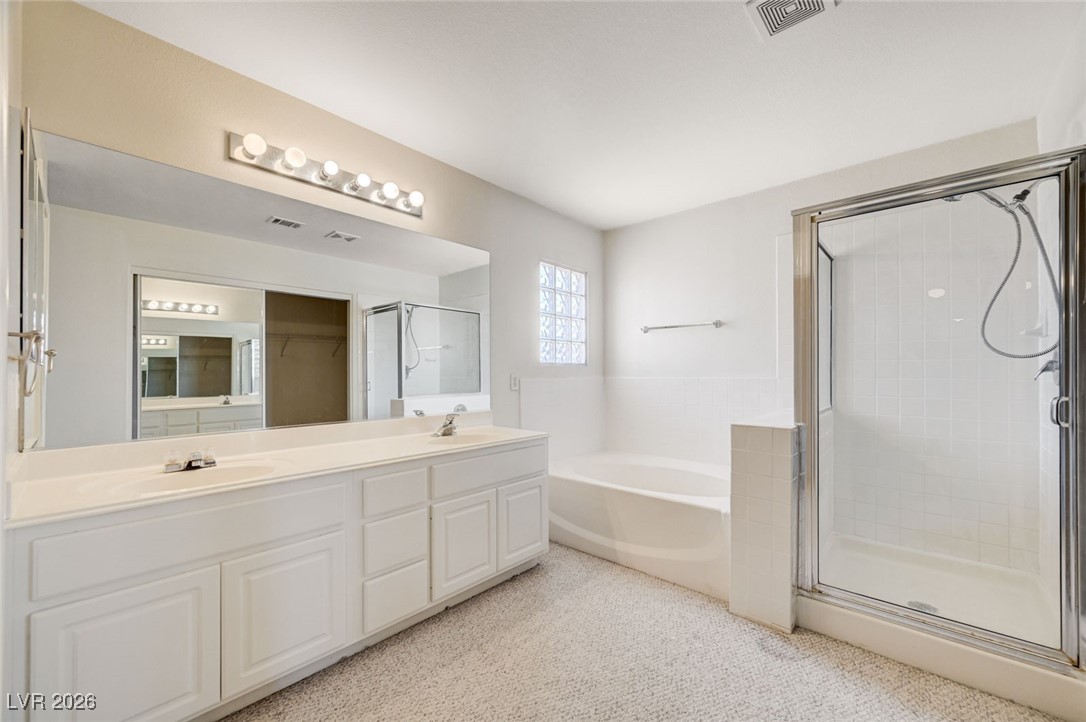 3901 Triora Street Las Vegas, NV 89129 - Photo 23 of 42 Bathroom featuring a bath, double vanity, a shower stall, and a spacious closet
