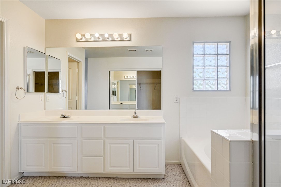 3901 Triora Street Las Vegas, NV 89129 - Photo 24 of 42 Full bathroom featuring double vanity, a garden tub, and a shower stall
