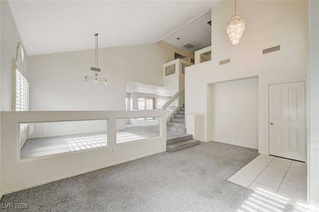 3901 Triora Street Las Vegas, NV 89129 - Photo 5 of 42 Entryway featuring a chandelier, light colored carpet, high vaulted ceiling, light tile patterned floors, and stairway