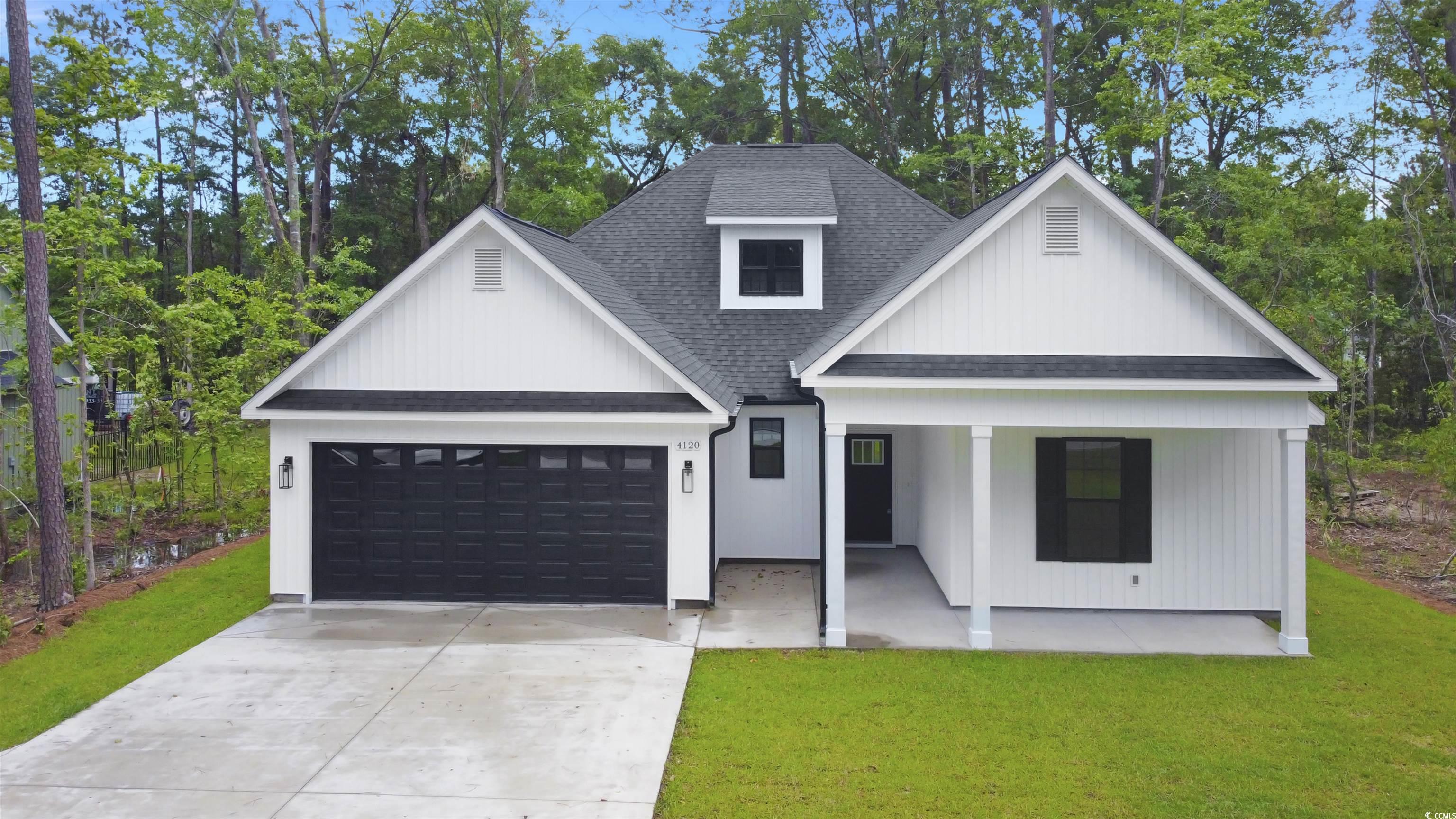 Modern farmhouse featuring roof with shingles, a porch, a garage, a front lawn, and concrete driveway