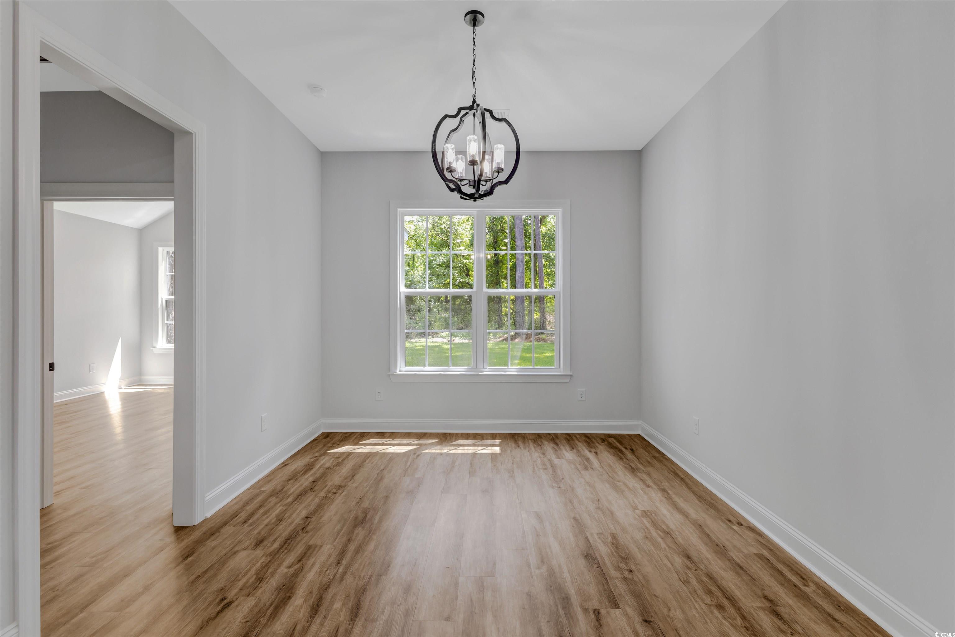 4121 Whatuthink Road Myrtle Beach, SC 29588 - Photo 13 of 28 Unfurnished dining area featuring a chandelier, LVP flooring, and baseboards
