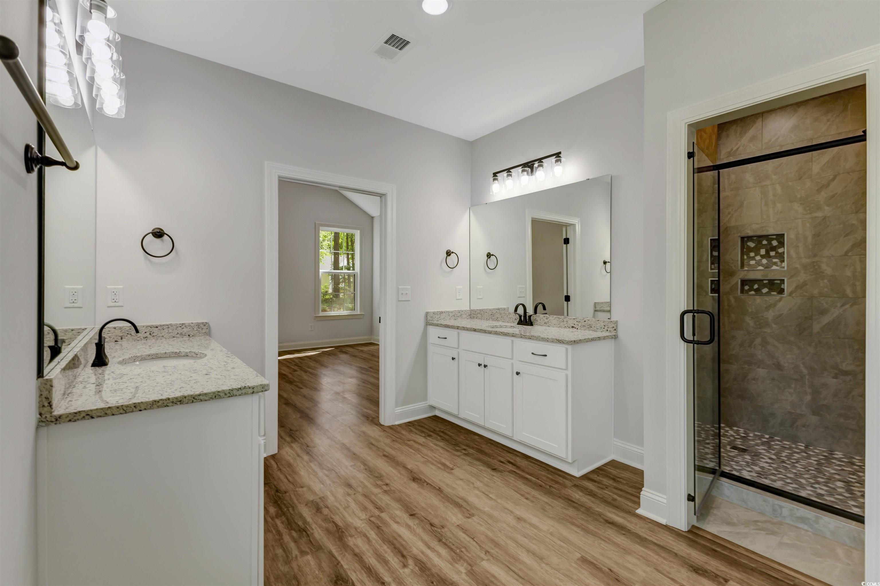 4121 Whatuthink Road Myrtle Beach, SC 29588 - Photo 19 of 28 Master Bathroom featuring a stall shower, two vanities, and baseboards