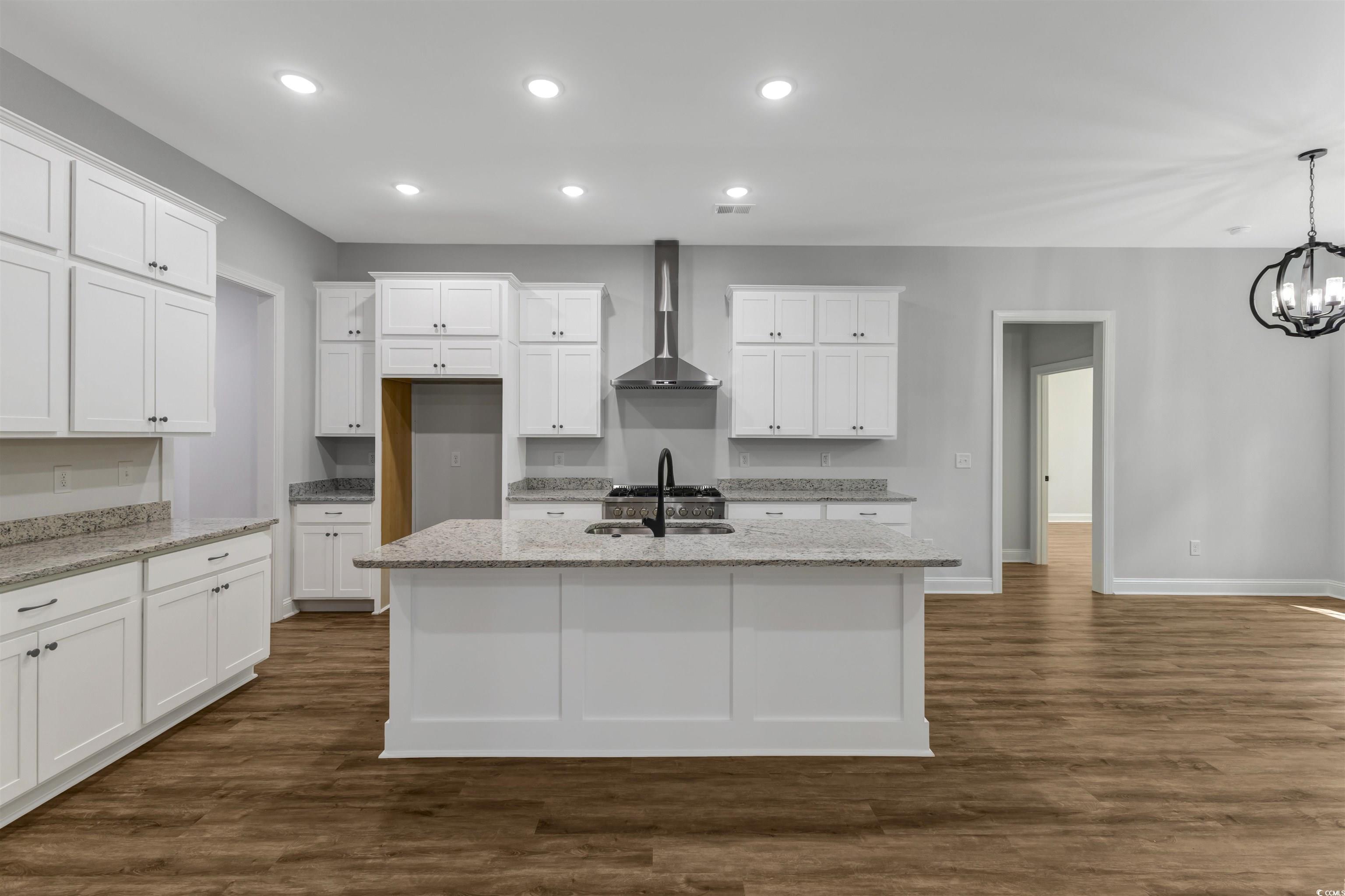 4121 Whatuthink Road Myrtle Beach, SC 29588 - Photo 9 of 28 Kitchen with wall chimney exhaust hood, a sink, baseboards, an island with sink, and LVP flooring