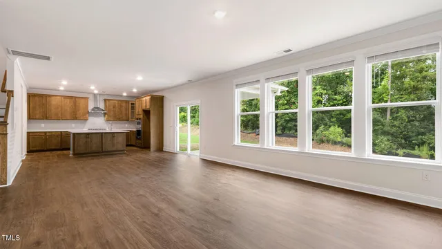 a view of an empty room with a window and kitchen view