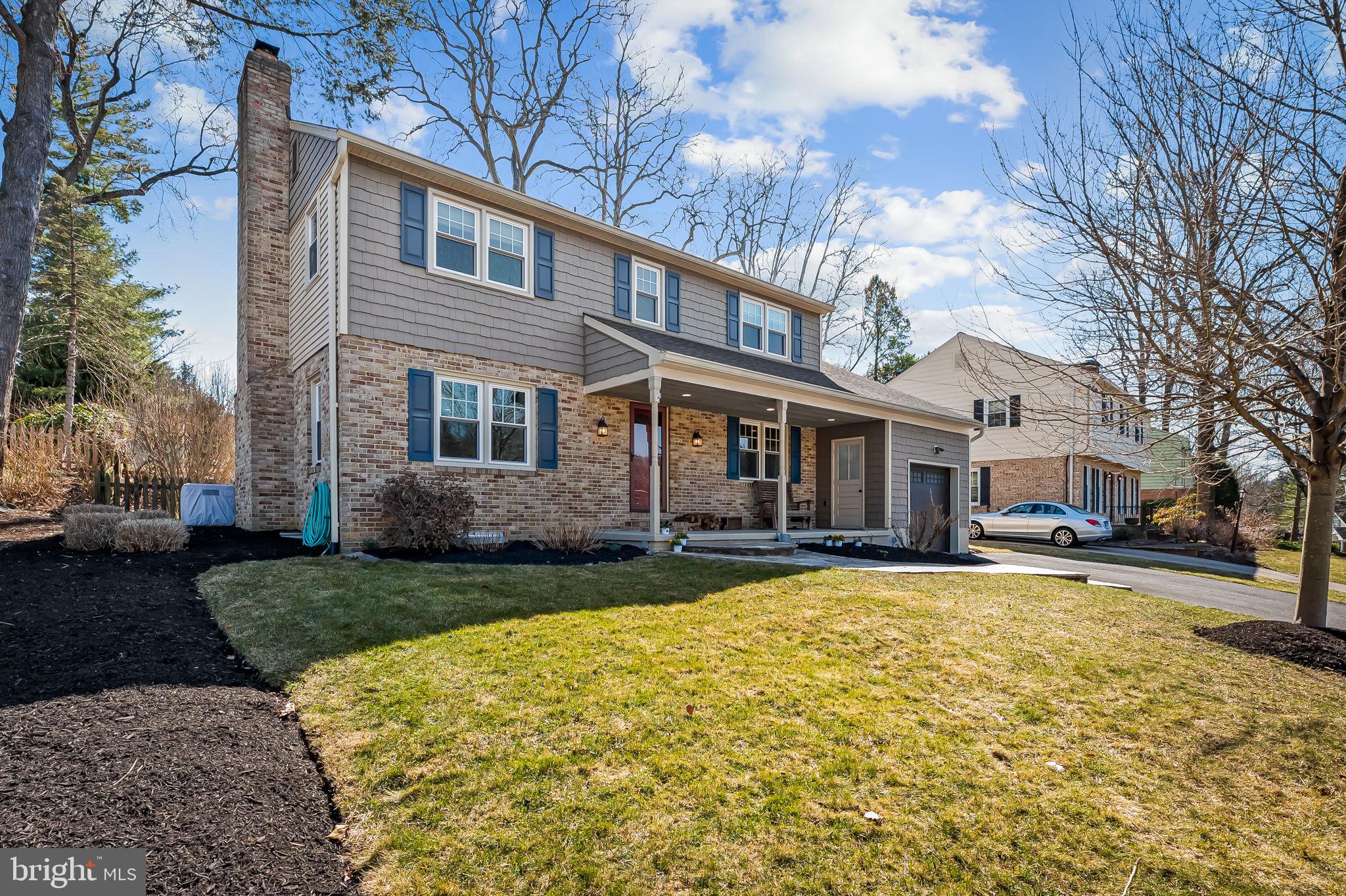 a view of a yard in front of a brick house with a large tree