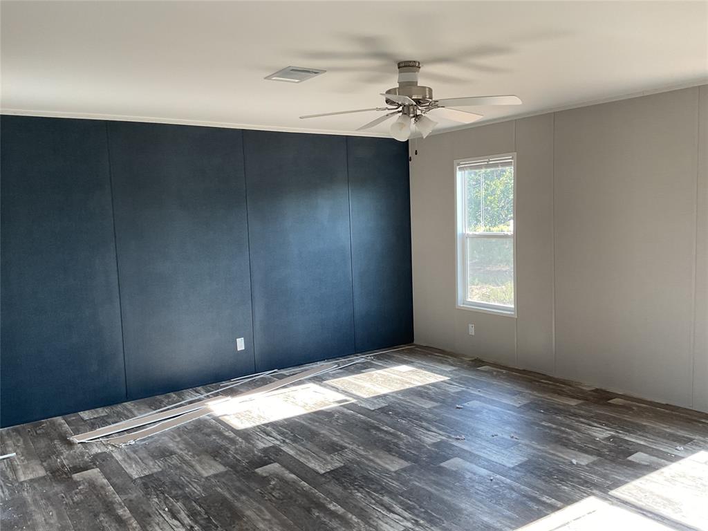 137 Firefly Drive Springtown, TX 76082 - Photo 4 of 12 Interior space featuring wood-finish flooring, a contemporary ceiling fan with integrated lighting, and a prominent dark accent wall