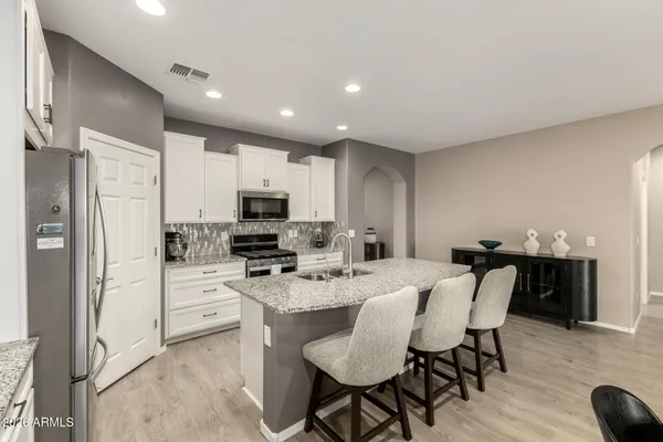 a kitchen with microwave a refrigerator and chairs