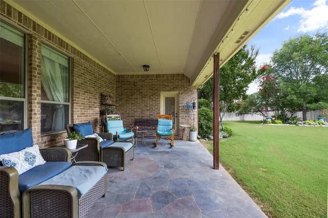 a view of a patio with couches table and chairs with plants and garden