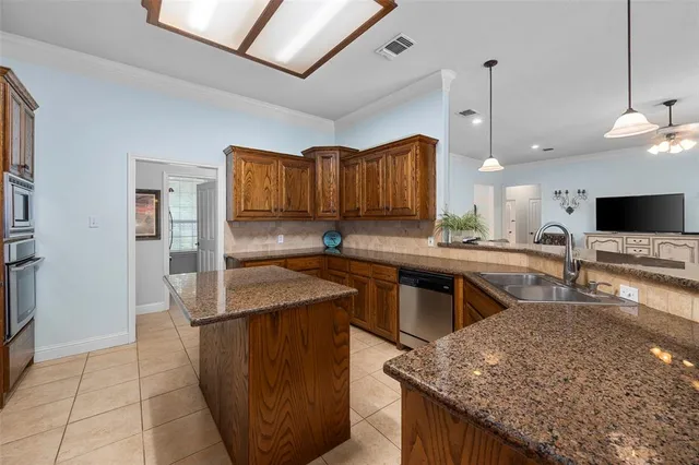 a kitchen with stainless steel appliances granite countertop a sink a stove and a wooden cabinets
