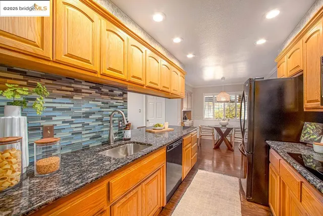 a kitchen with stainless steel appliances granite countertop a sink stove and refrigerator