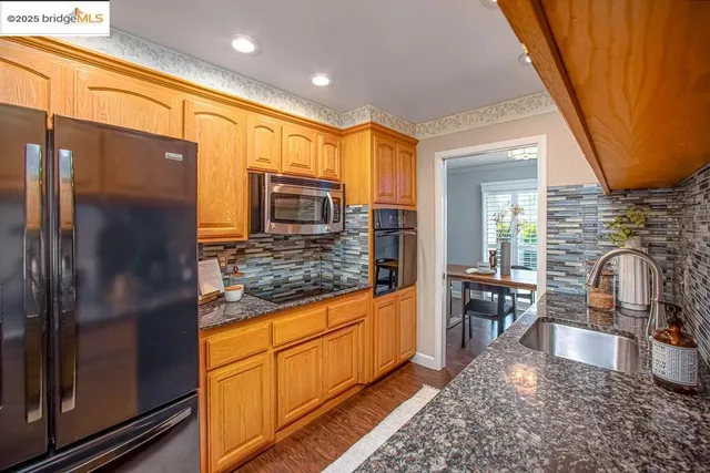 a kitchen with stainless steel appliances granite countertop sink stove refrigerator and cabinets