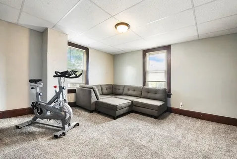 a living room with furniture a window and gym equipment