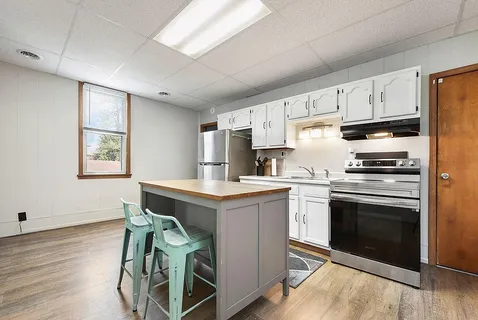 a kitchen with cabinets wooden floor and stainless steel appliances