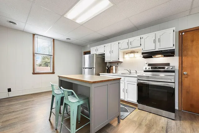 a kitchen with cabinets wooden floor and stainless steel appliances