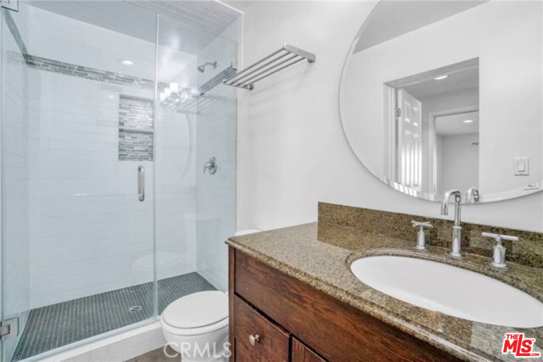 5003 Tilden Avenue, Unit 109 Sherman Oaks, CA 91423 - Photo 14 of 29 a bathroom with a granite countertop sink toilet a mirror and shower