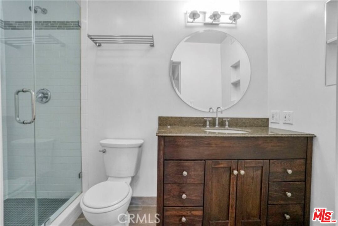 5003 Tilden Avenue, Unit 109 Sherman Oaks, CA 91423 - Photo 16 of 29 a bathroom with a granite countertop toilet a sink and mirror
