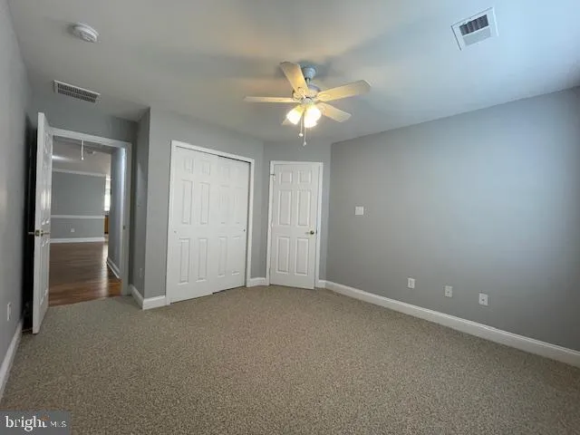 an empty room with closet and a chandelier fan