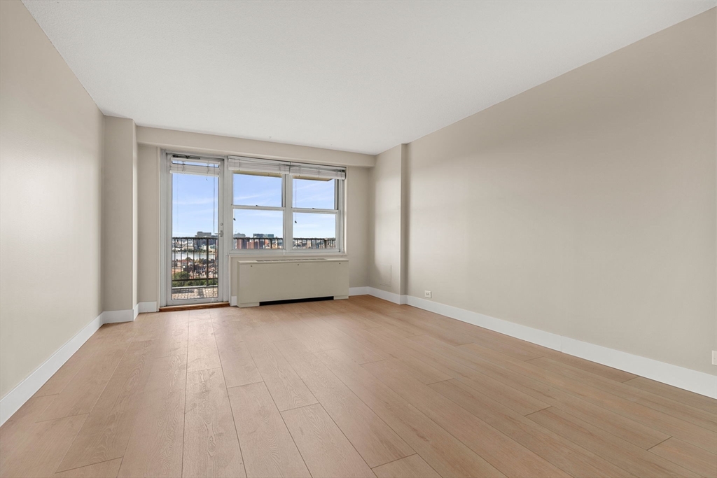 151 Tremont Street, Unit 23P Boston, MA 02111 - Photo 12 of 35 an empty room with wooden floor and glass door